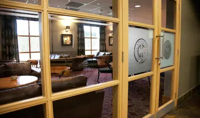 a room with glass doors and leather chairs and tables at Castlecary House Hotel in Cumbernauld