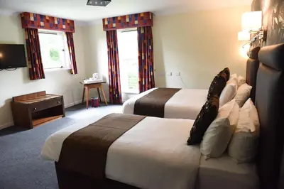 a hotel room with two beds and a television at Castlecary House Hotel in Cumbernauld
