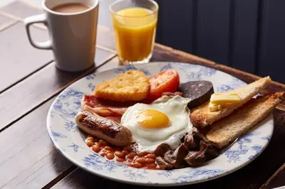 a plate of breakfast food with eggs sausage beans and toast at The Titan By Greene King Inns in Clydebank