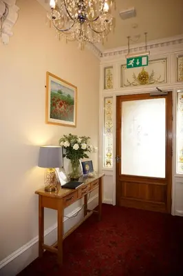 a room with a desk with a lamp and a window at Braidmead House in Irvine