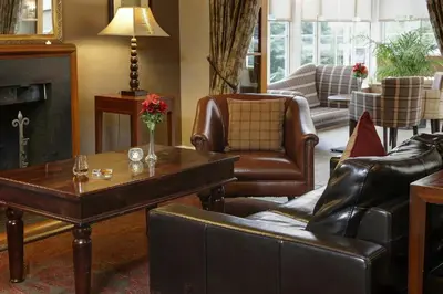 a living room with leather furniture and a fireplace at Buchanan Arms Hotel & Leisure, Sure Hotel Collection in Drymen