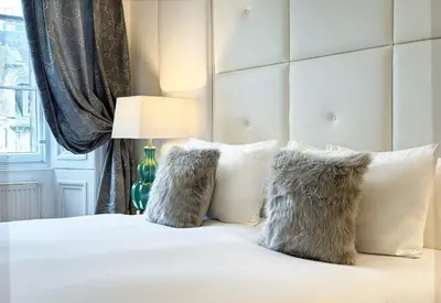 a bedroom with a white bed with white pillows at Hanover 71 Suites in Edinburgh