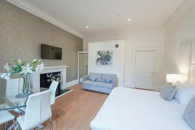 a bedroom with a white bed and a living room at Hanover 71 Suites in Edinburgh