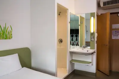 a bedroom with a bed and a sink and a mirror at ibis budget Glasgow in Glasgow
