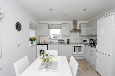 a kitchen with white cabinets and a table with flowers on it at 6 Beech Court in Dunblane
