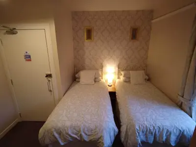 two beds in a small room with a light between them at Inverardran House in Crianlarich