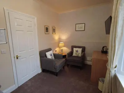 a room with two chairs and a table with a lamp at Inverardran House in Crianlarich