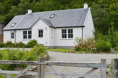 a white house with a fence in front of it at Teal Cottage in Clachan of Glendaruel
