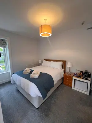 a bedroom with a large bed and a lamp at Ronebhal Guest House in Oban