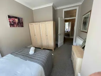 a bedroom with a bed and a wooden cabinet at Apartment 2 Bed West End in Glasgow