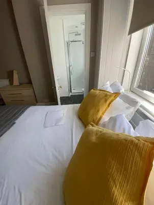 a bedroom with a bed with white sheets and yellow pillows at Apartment 2 Bed West End in Glasgow