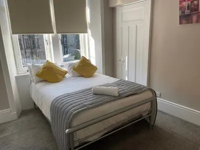 a bedroom with a bed with yellow pillows and a window at Apartment 2 Bed West End in Glasgow