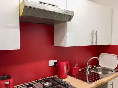 a red kitchen with a sink and a stove at Watson Crescent in Edinburgh