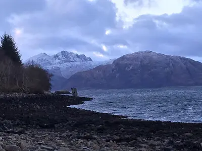 a body of water with mountains in the background at Woodland Cabins, Glencoe in Ballachulish