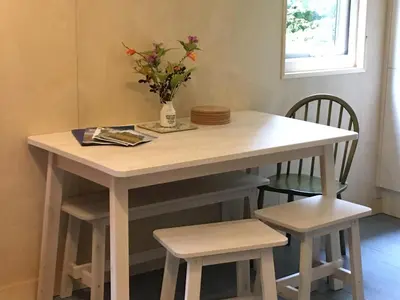 a white table with two chairs and a vase with flowers at Woodland Cabins, Glencoe in Ballachulish