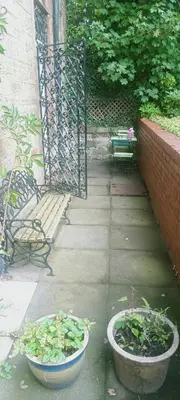 a patio with two pots of plants and a bench at Fountainbridge Flat in Edinburgh