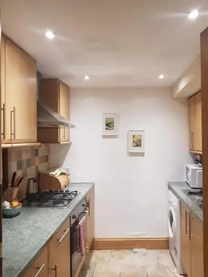 a kitchen with wooden cabinets and a stove top oven at Fountainbridge Flat in Edinburgh