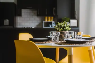 a table with plates and glasses on it with yellow chairs at SuperbSleep Apartments in Glasgow