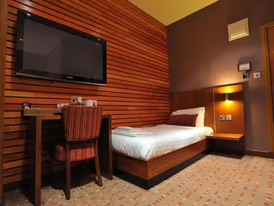 a hotel room with a bed and a flat screen tv at The Commercial Hotel in Wishaw