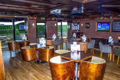 a restaurant with wooden tables and chairs and a brick wall at The Commercial Hotel in Wishaw