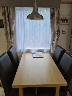 a dining room table with chairs and a window at Bear Lodge in Auchterarder