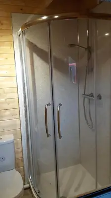 a glass shower in a bathroom with a toilet at Lochinvar - Highland Log Cabin with Private Hot Tub in Airdrie