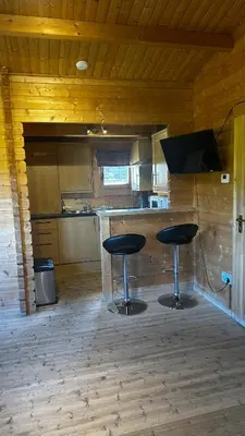 a kitchen with two stools and a bar in a cabin at Lochinvar - Highland Log Cabin with Private Hot Tub in Airdrie