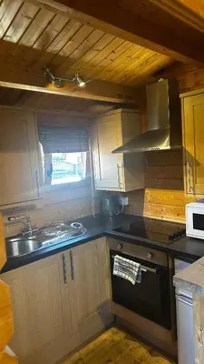 a small kitchen with a sink and a stove at Lochinvar - Highland Log Cabin with Private Hot Tub in Airdrie
