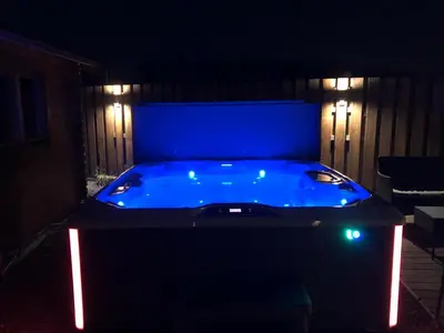a blue hot tub in a backyard at night at Lochinvar - Highland Log Cabin with Private Hot Tub in Airdrie
