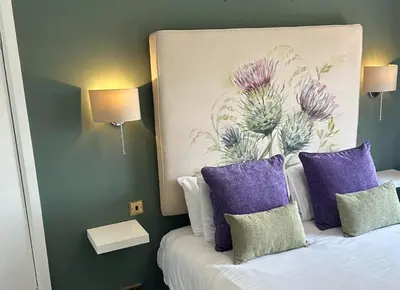 a bedroom with a bed with purple pillows and a painting at The Tontine Hotel in Greenock