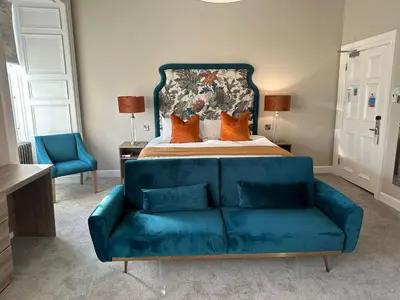 a blue couch in a bedroom with a bed at The Tontine Hotel in Greenock