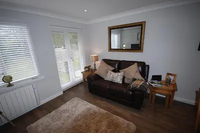 a living room with a leather couch and a mirror at The Beeches at Gleneagles in Auchterarder
