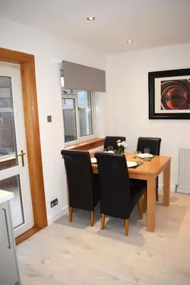 a dining room with a wooden table and black chairs at Kelpies Serviced Apartments- Russell in Falkirk
