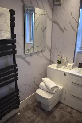 a bathroom with a white toilet and a mirror at Kelpies Serviced Apartments- Russell in Falkirk