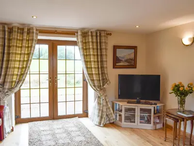a living room with a television and sliding glass doors at The Ploughmans - Uk5531 in Kepculloch