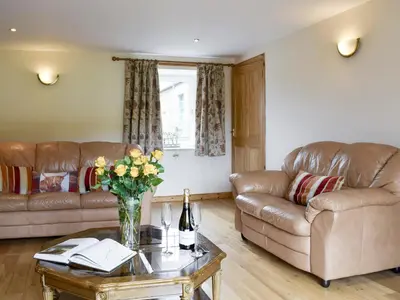 a living room with two couches and a table with flowers at The Stables - Uk5532 in Kepculloch