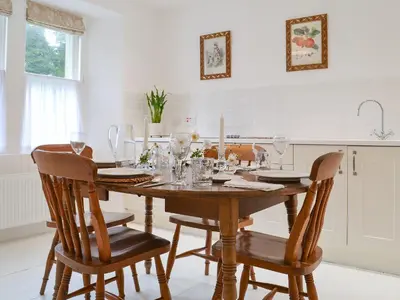 a kitchen with a wooden table with chairs and wine glasses at Garden Cottage in Strachur