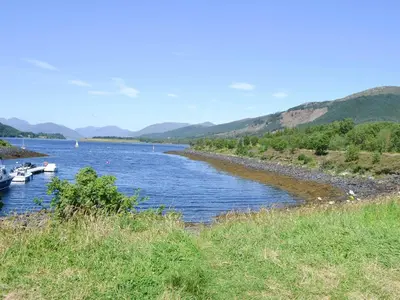 a river with boats on it with mountains in the background at River Mill House in Ballachulish