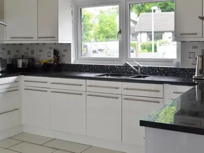a white kitchen with a sink and two windows at River Mill House in Ballachulish
