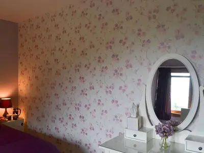 a bedroom with a mirror and flowers on the wall at River Mill House in Ballachulish