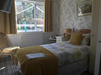 a hotel room with a bed and a window at glenardran house in Crianlarich