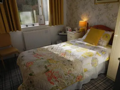 a bedroom with a bed with a quilt on it at glenardran house in Crianlarich