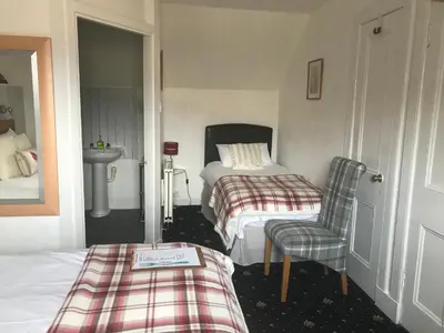 a bedroom with two beds and a chair and a sink at glenardran house in Crianlarich