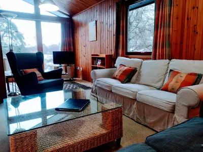 a living room with two couches and a glass table at Loch Monzievaird Chalets in Crieff