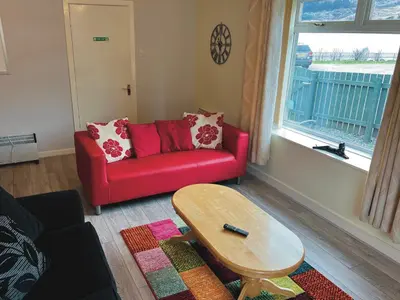 a living room with a red couch and a table at Feorline Cottage in Lochgoilhead