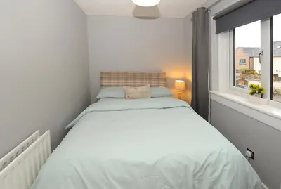 a small bedroom with a bed and a window at Three Bedroom Spacious House in Stirling