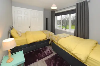 a bedroom with two beds and a window at Three Bedroom Spacious House in Stirling