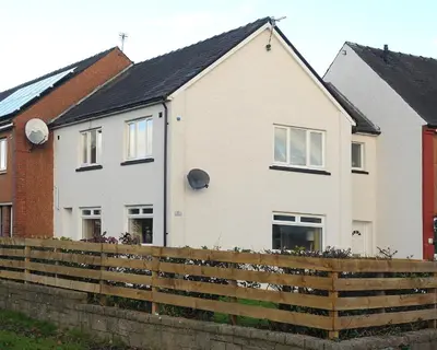 a white house with a fence in front of it at Three Bedroom Spacious House in Stirling