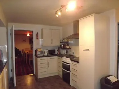 a kitchen with white cabinets and a white refrigerator at Gorsnavoon Cottage in Clachaig