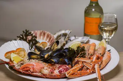 a plate of seafood on a table with a bottle of wine at Bridgend Hotel in Bridgend